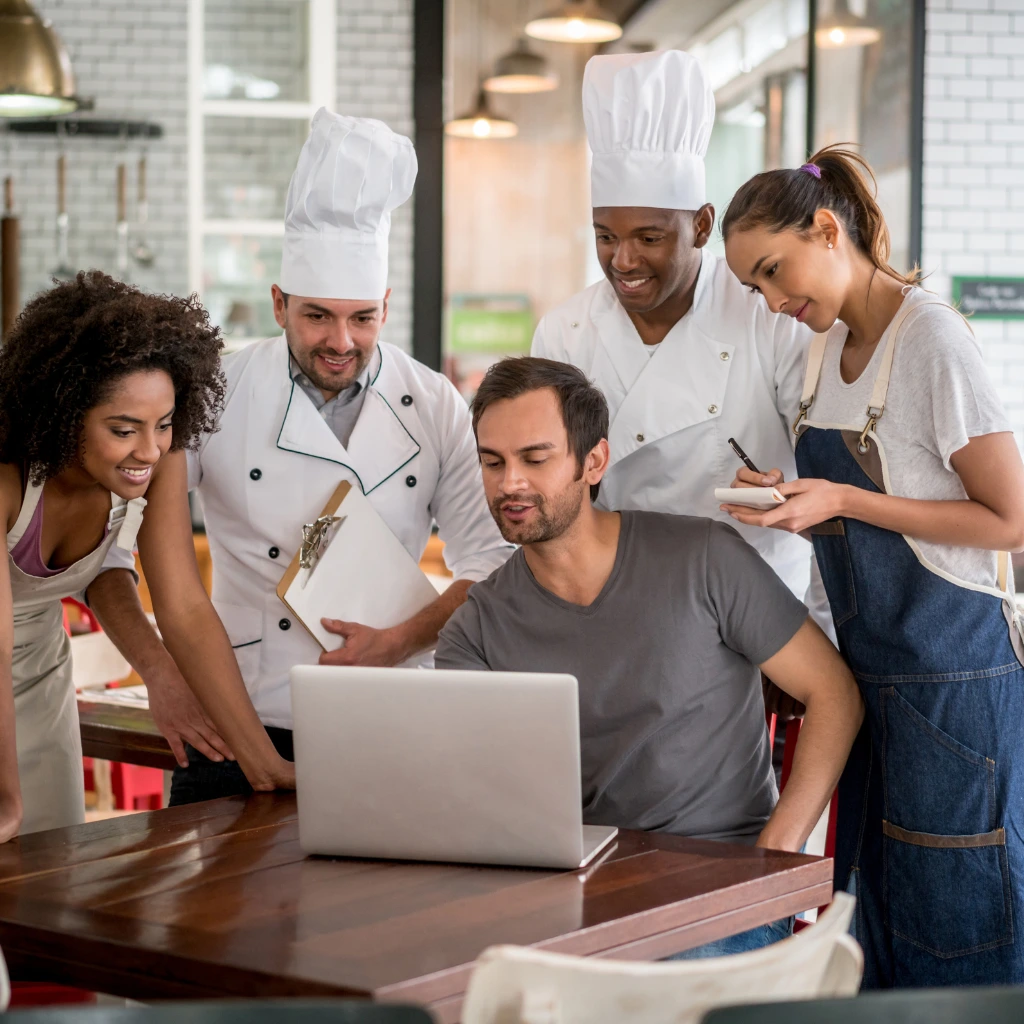 Restaurant team reviewing IT systems on a laptop in a commercial kitchen