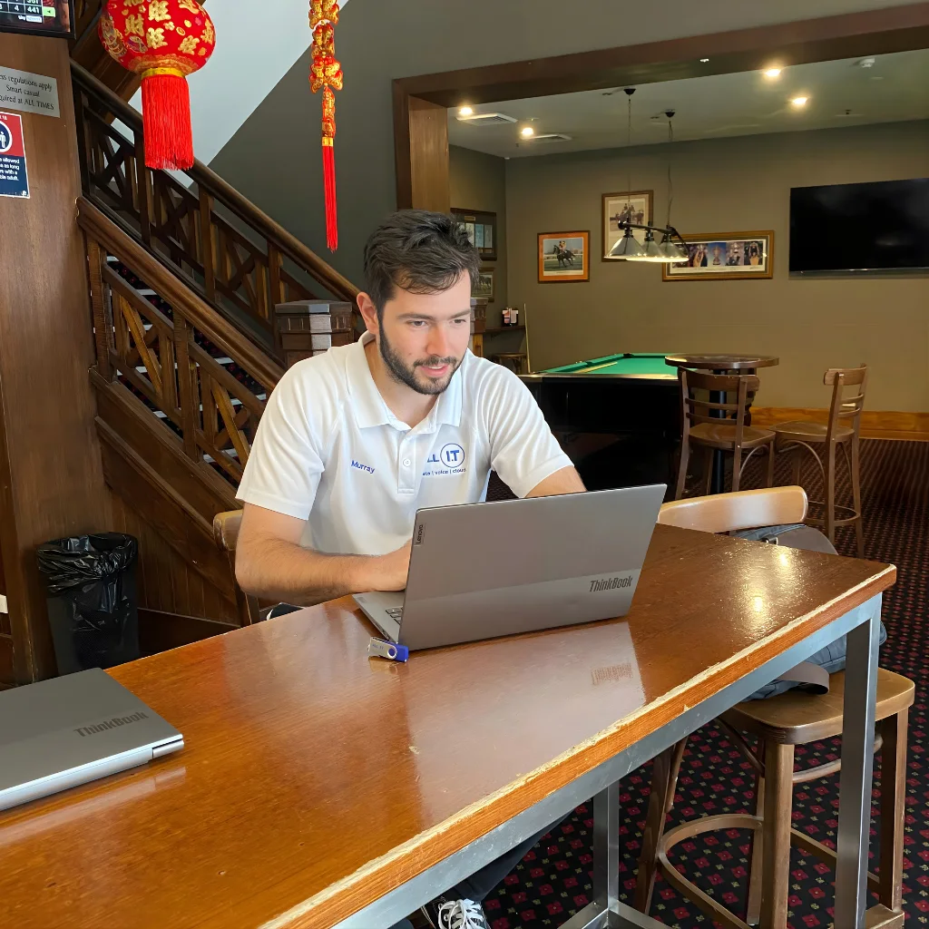 ALL IT technician configuring a laptop on-site at a pub